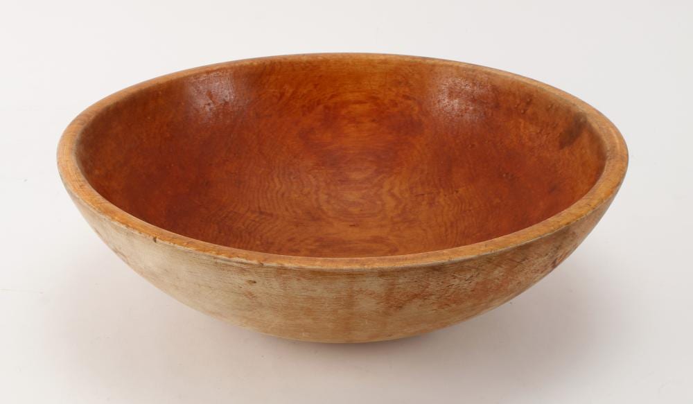 Large round wooden dough bowl with shallow sides and worn natural finish, photographed against a light background.
