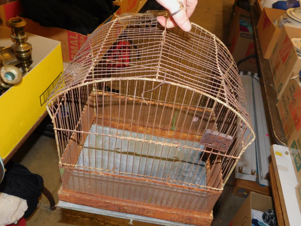 Antique-looking metal birdcage with a circular top and rusted base, viewed indoors.