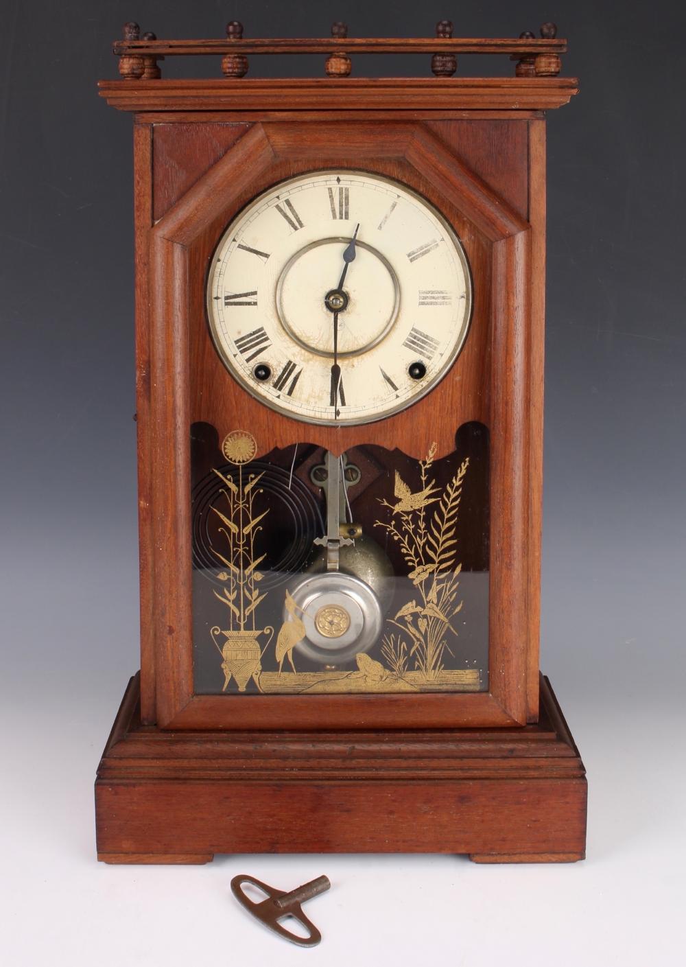 Wooden mantel clock with round white clock face, black roman numerals, and decorative gold-painted panel below the dial.