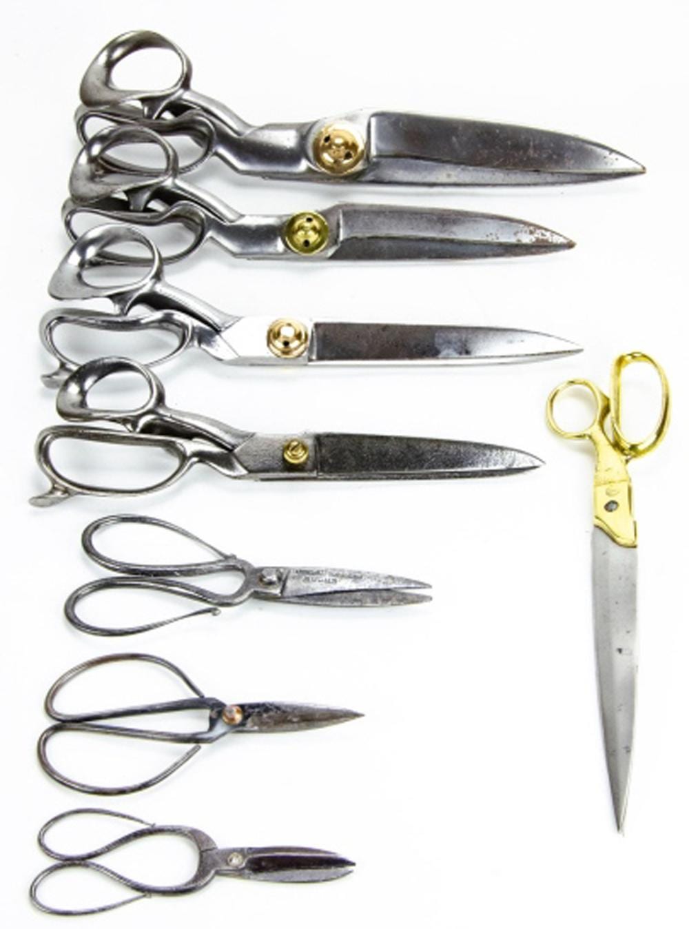 Collection of vintage tailor’s shears and small scissors with metal blades and ring handles, shown against a white background.