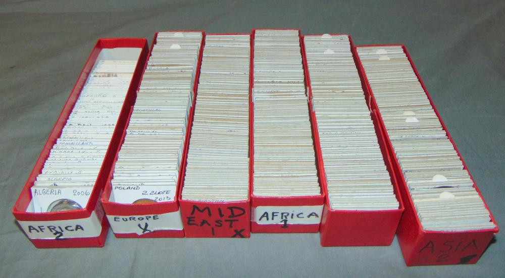 Several stacks of coins in red trays labeled Africa, Europe, America, and Asia.