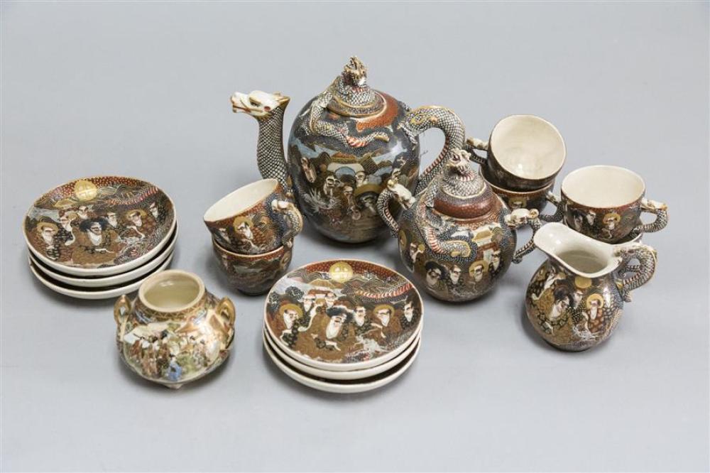 Group photo of a Japanese Kutani-style porcelain tea service with dragon-and-figure decorations, including teapot, cups, and covered containers on a light gray/