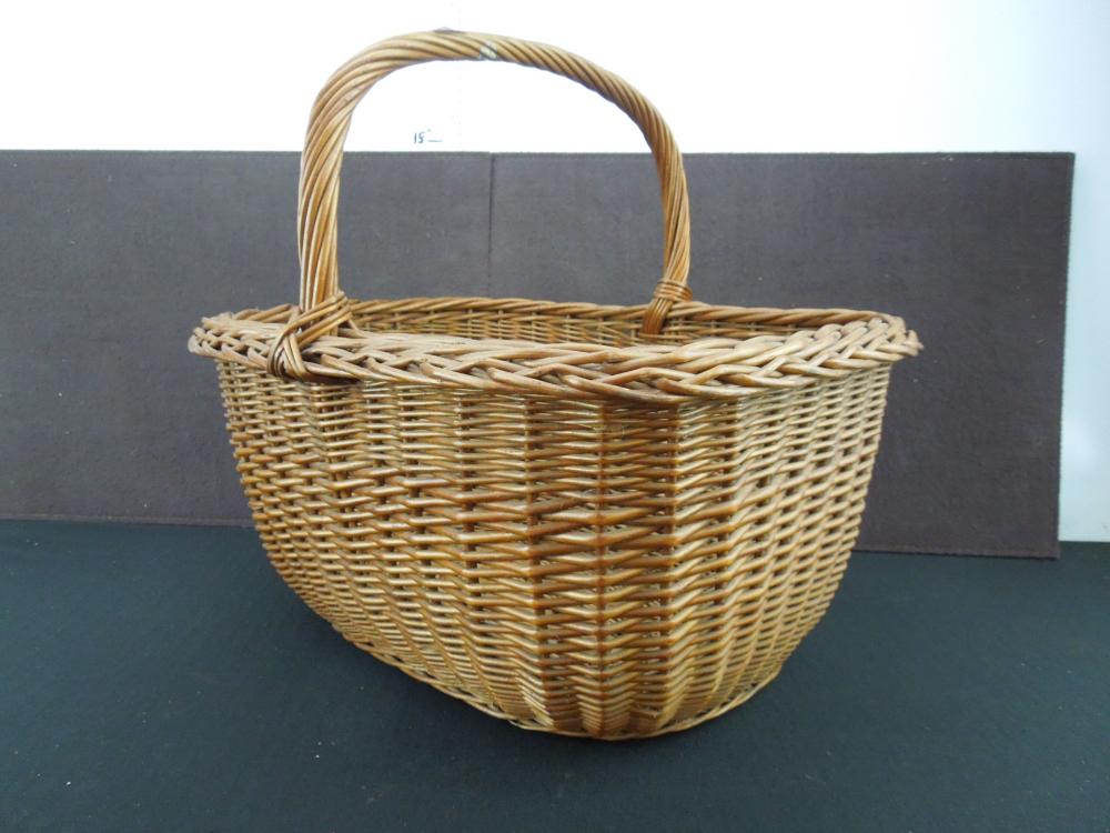 Wicker picnic basket with a curved handle and woven basket body on a dark background.