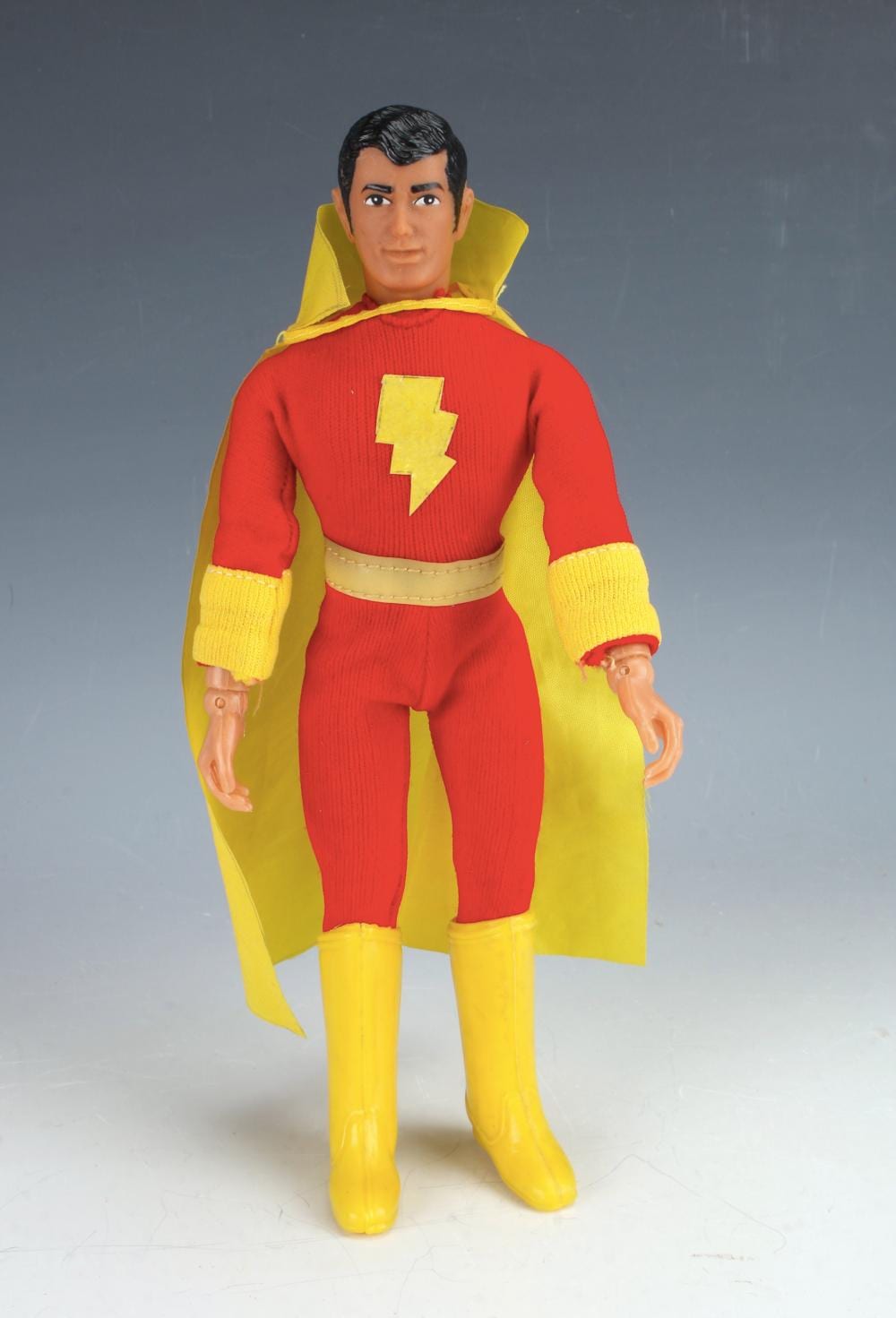 Standing action figure doll in red and yellow outfit with a lightning-bolt emblem on the chest and long yellow gloves.