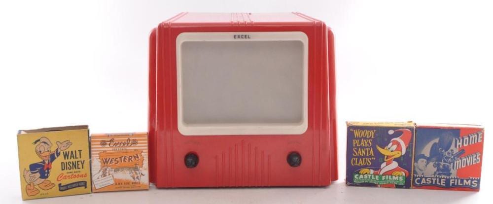 Red vintage movie projector with a screen window and two speakers, shown with several boxed film reels on a white background.
