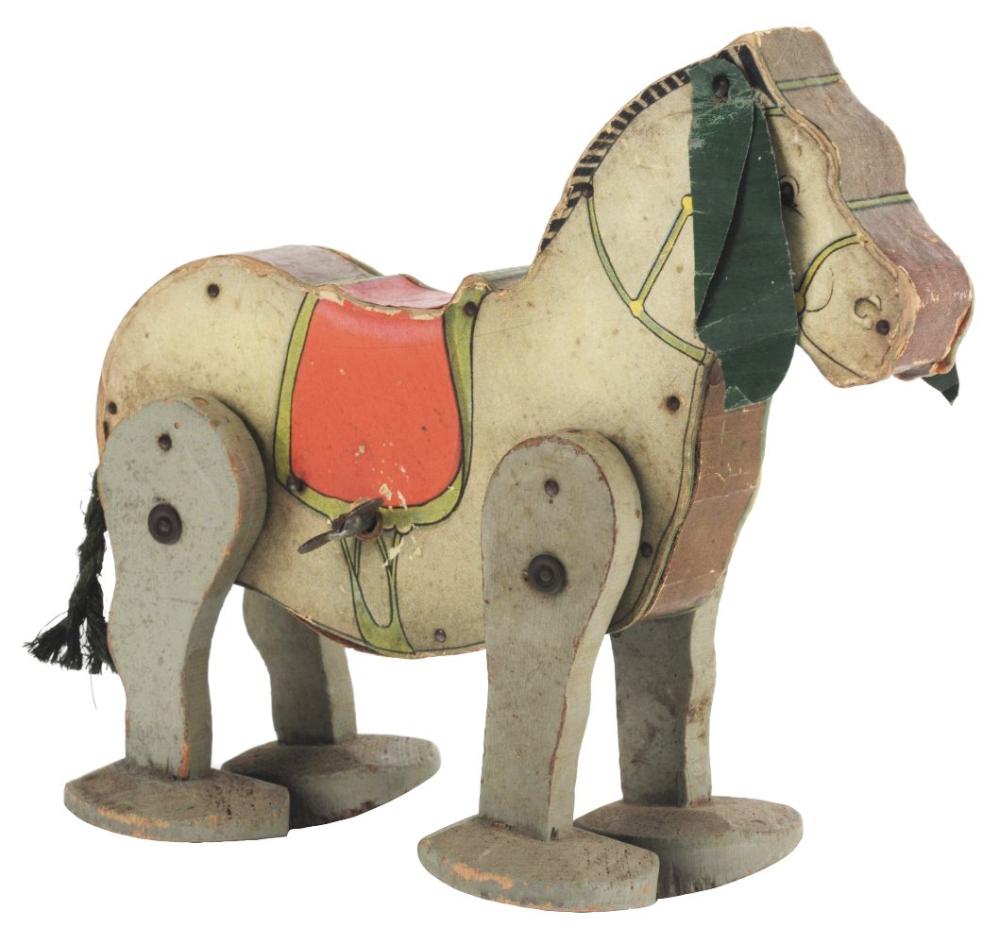 A vintage painted wooden wind-up mule toy with two side wheels and a red saddle, on a white background.