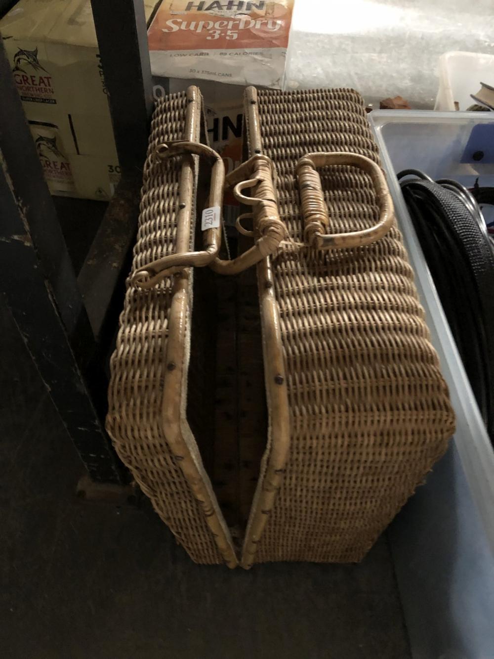 Wicker picnic basket with curved handle, shown from the side, with storage contents partially visible.