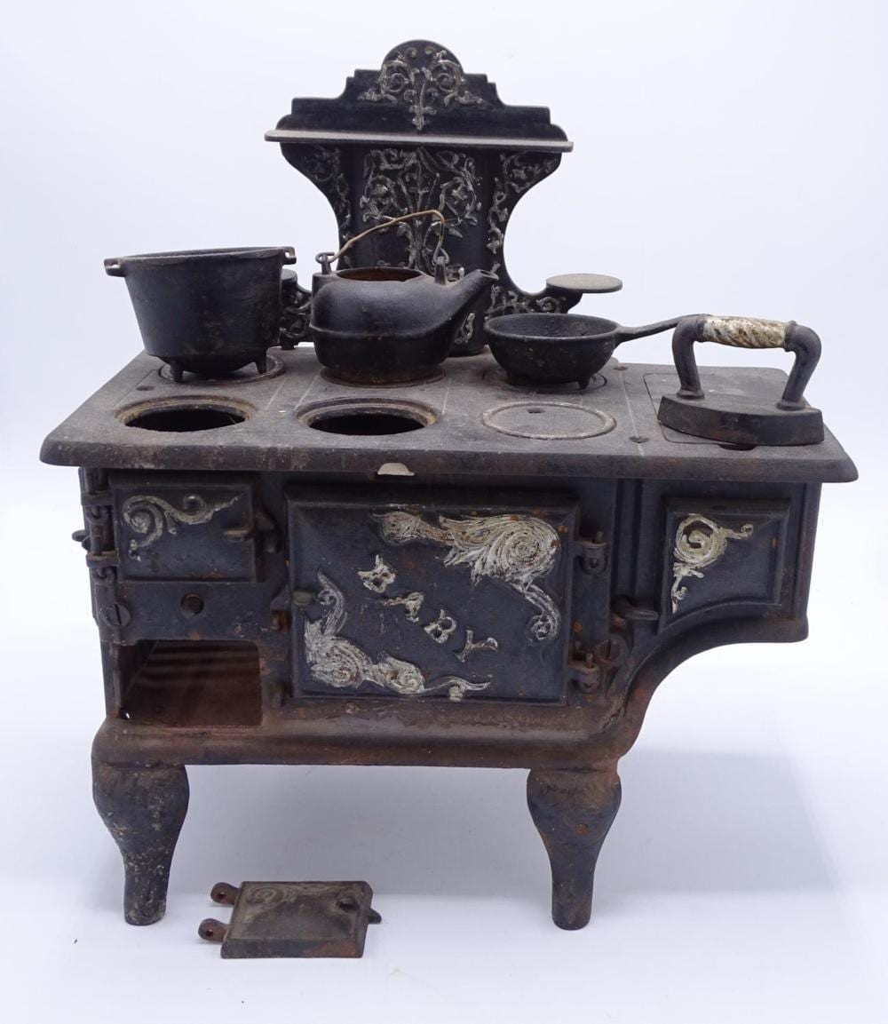 Cast iron stove salesman's sample with ornate top, four burners, and a pot and pans arrangement