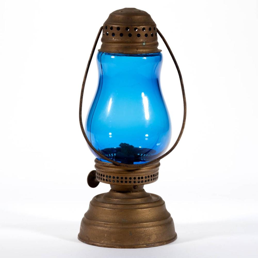 Brass oil skater’s lantern with a blue glass reservoir and perforated metal chimney, standing upright with a curved handle.