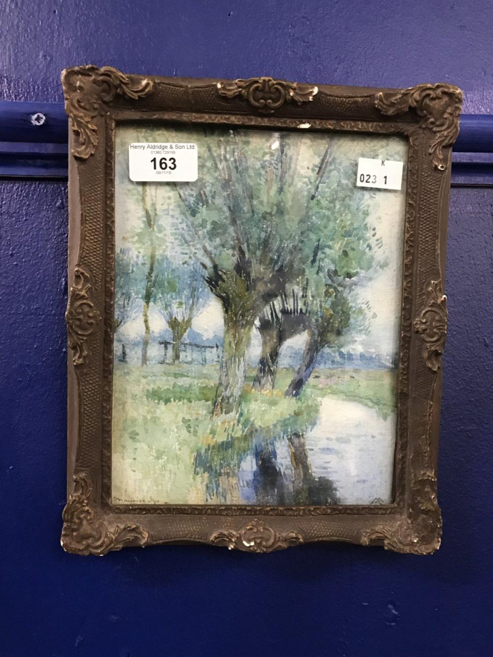 Framed watercolour painting of a riverside landscape with trees and a river, shown against a blue wall.