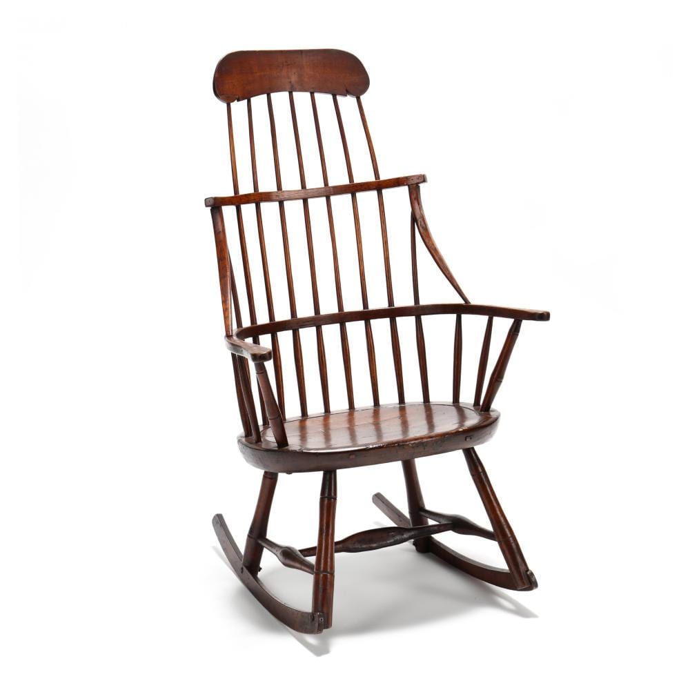 Wooden Windsor rocking chair with spindle backrest, curved armrests, and a cushioned seat, shown on a white background.