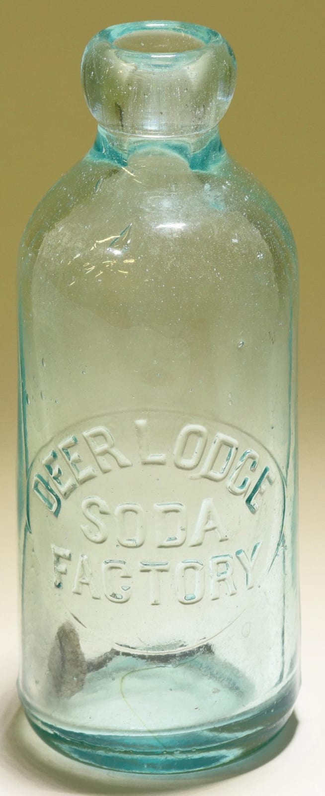 Close-up of a light blue glass soda bottle with a molded label reading “BEER-ODLEZ” and “USA FAMILY.”