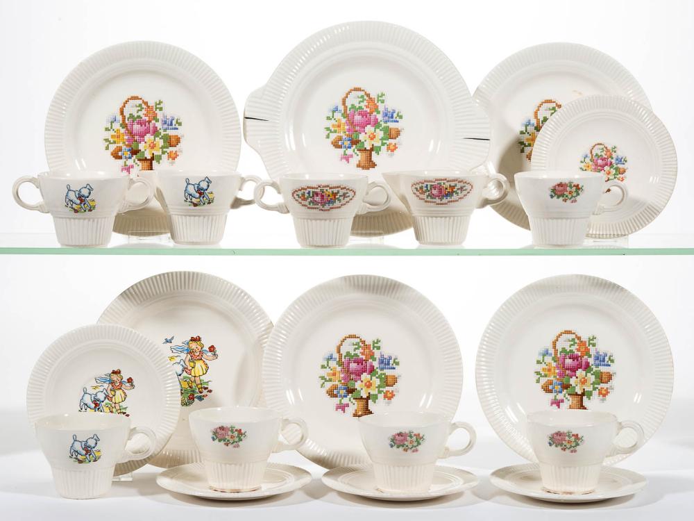 Group photo of white ceramic children's toy tea set pieces with small multicolor floral and animal illustrations on cups, saucers, and plates.