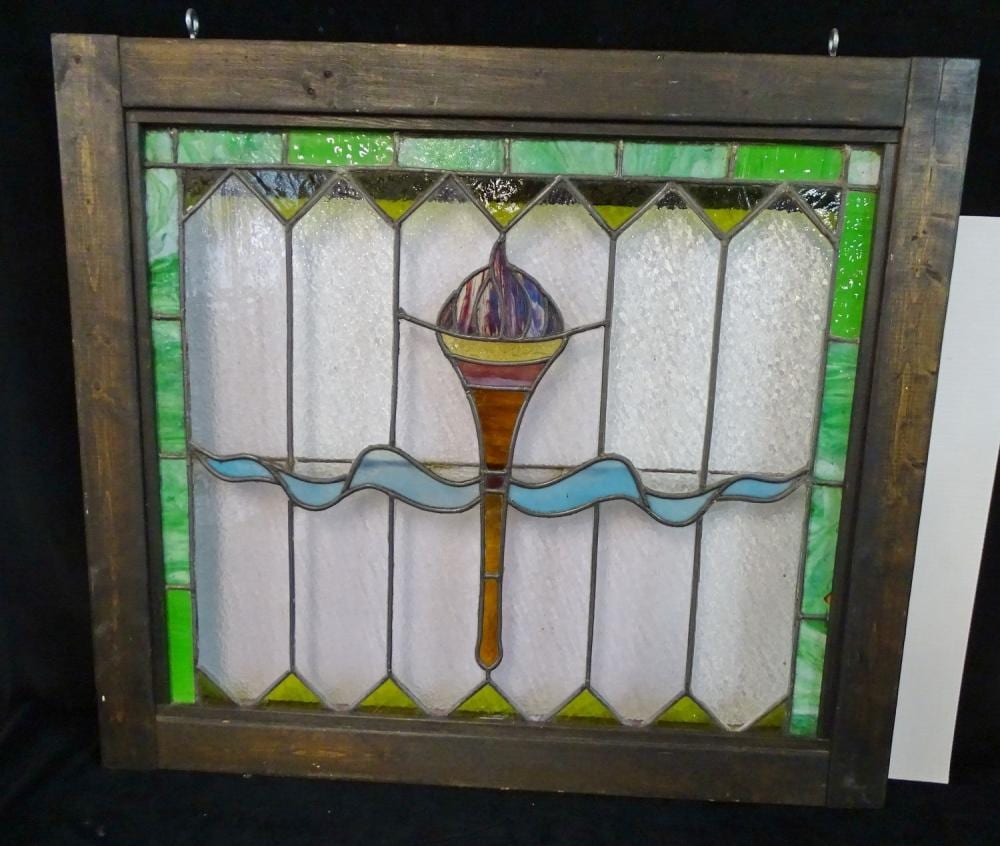 Framed leaded stained glass panel with a central chalice and wavy blue water band, surrounded by white diamond panes and green borders.