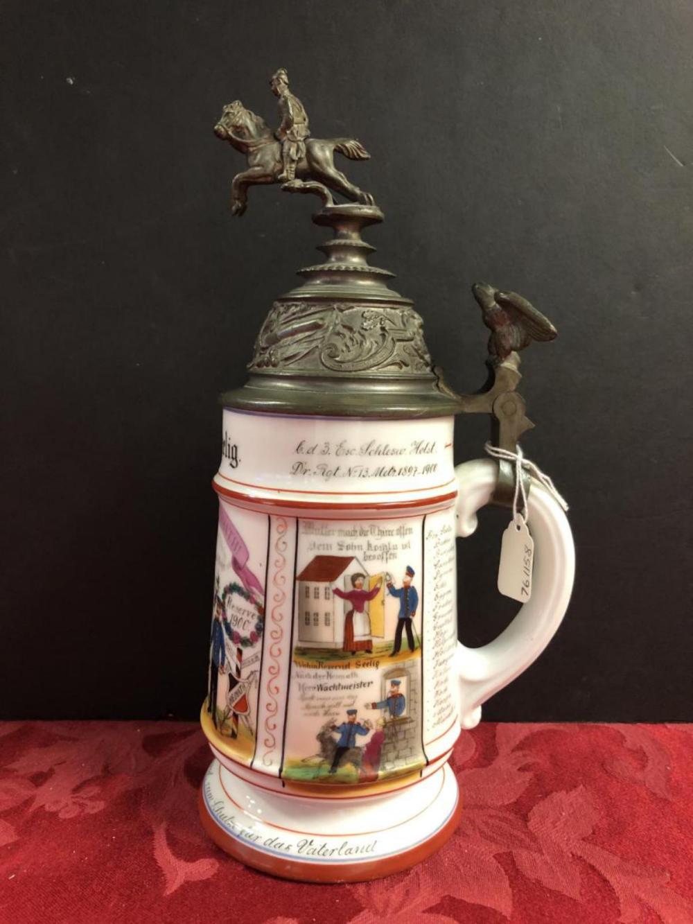 Decorative lidded ceramic beer stein with a metal horseman finial and colorful painted scenes on the body.