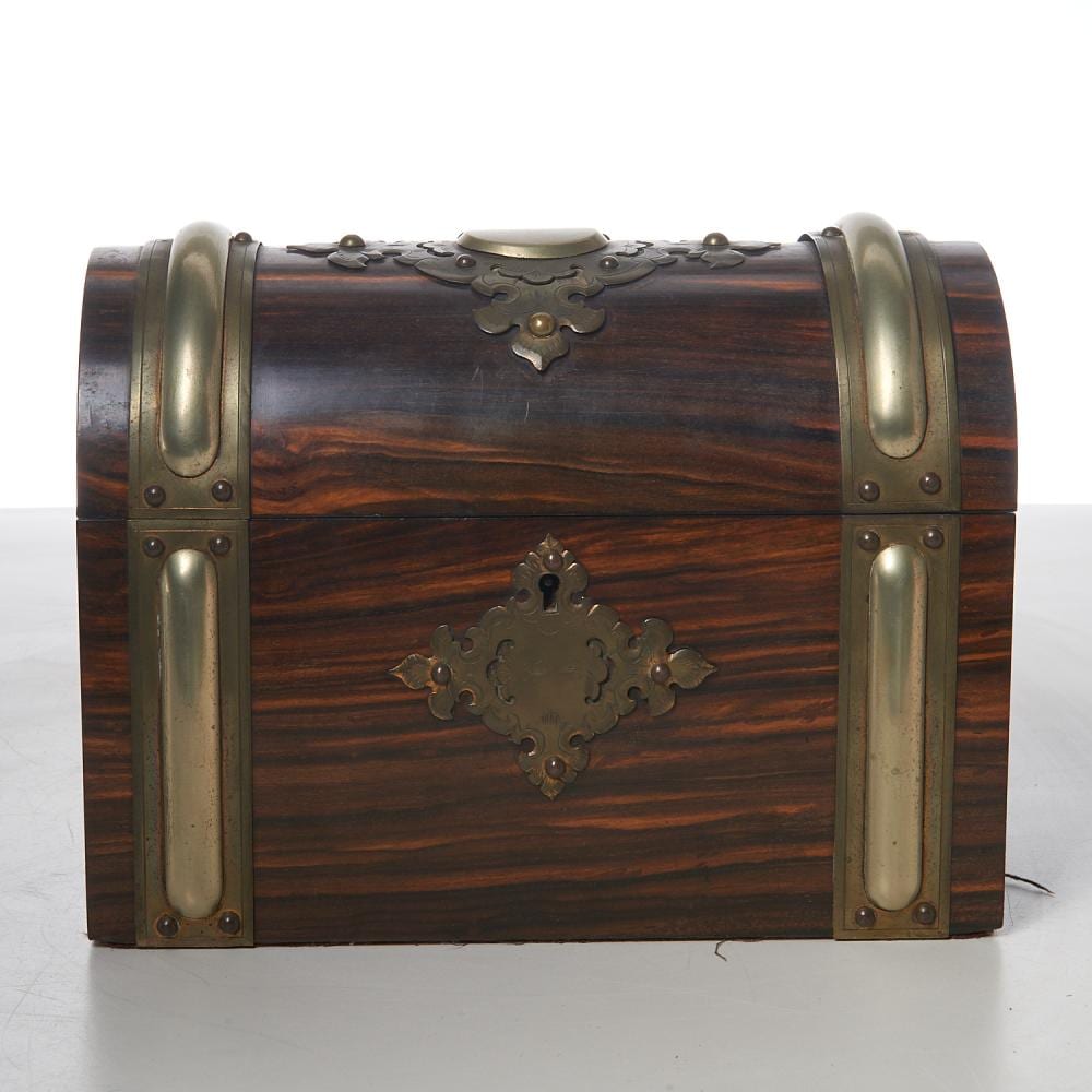 Brown wooden jewelry casket with brass corner fittings and ornate metal latch panels on the front and top.