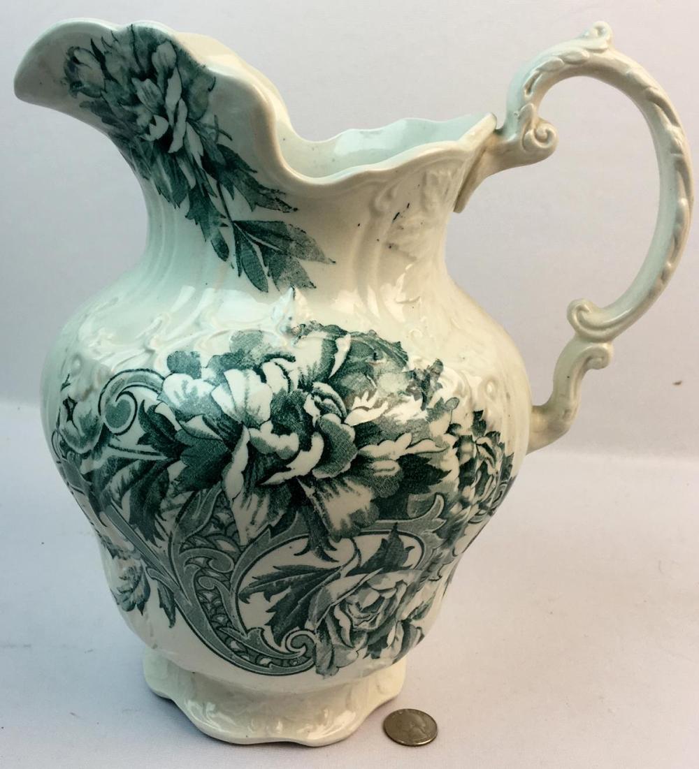 White ceramic pitcher with a green floral transfer-print pattern and a curved handle, photographed against a light background.