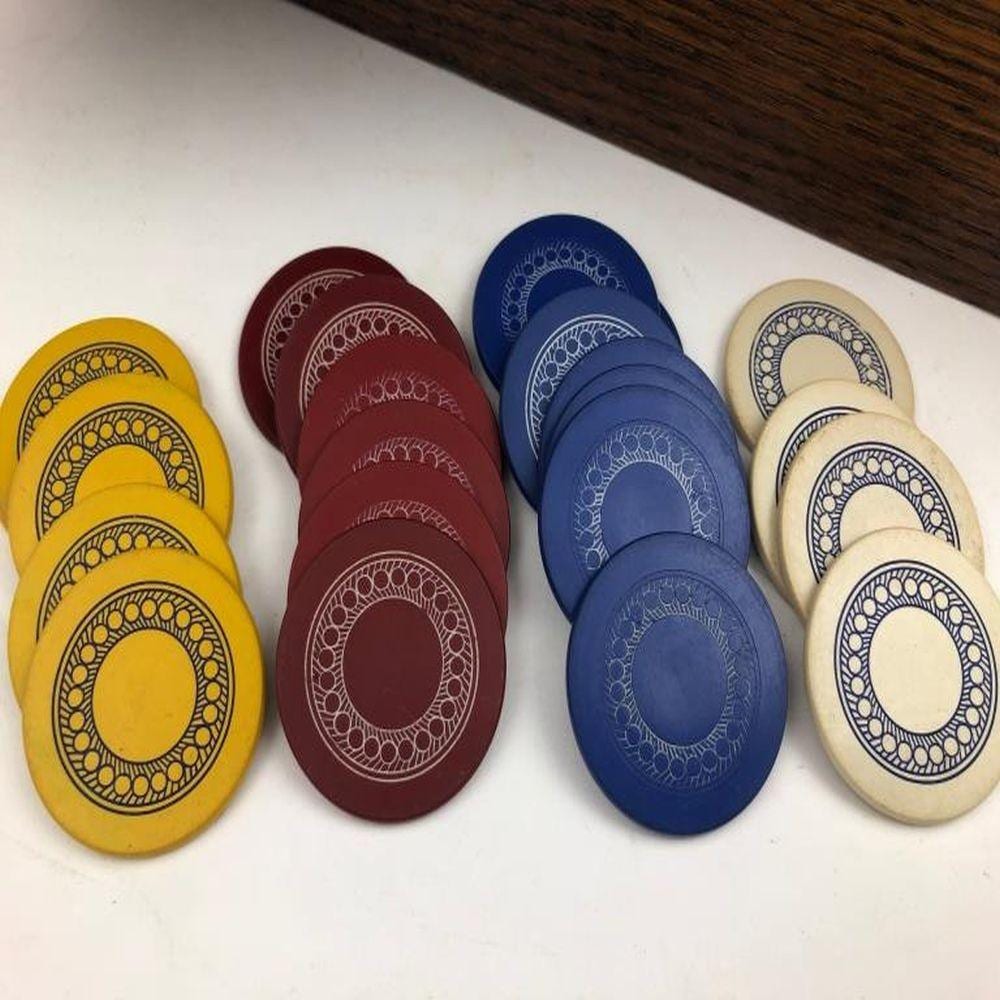 Colorful poker chips with circular lace-like patterns in yellow, maroon, blue, and cream, laid on a white surface.
