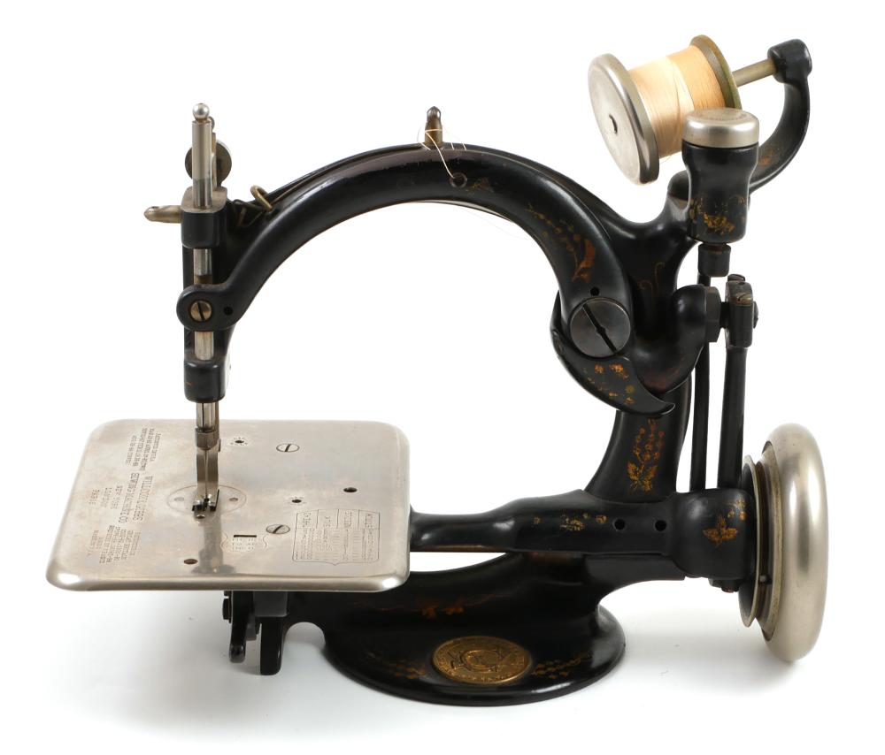 Black metal vintage sewing machine with a hand wheel, needle bar, and rectangular base plate on a white background.