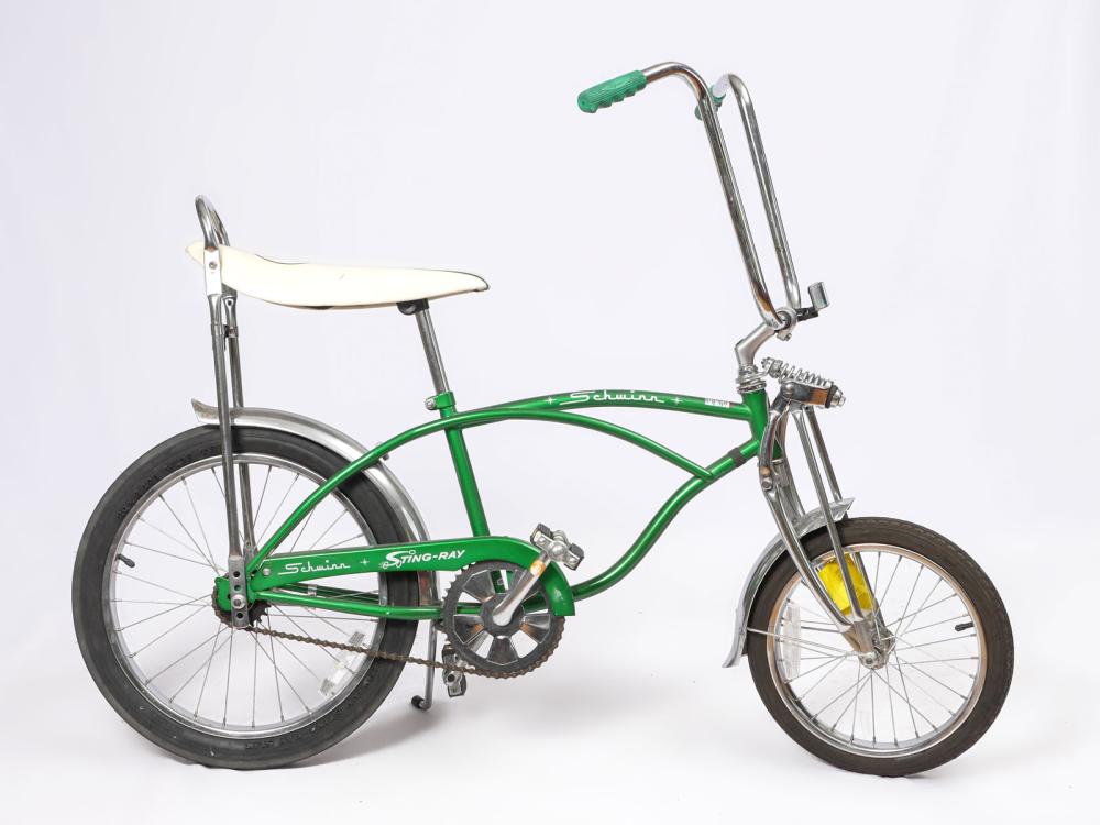 Green Schwinn Sting-Ray miniature bicycle with white seat and black tires on a white background, shown side view.