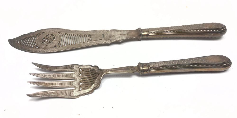 Close-up of a fish-serving fork and knife with ornate handles and a fish-shaped blade design.