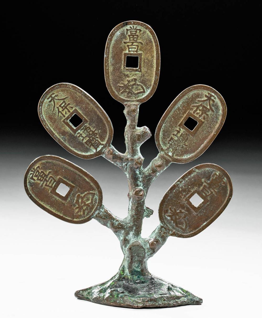Bronze coin money tree with five oval coins on branching stand, each coin stamped with characters, on a dark background.