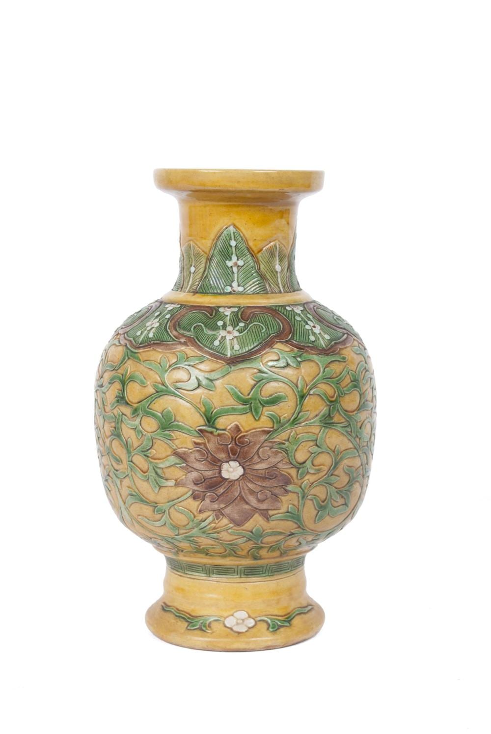 Decorated ceramic vase with a flared neck and rounded body, covered in green and yellow floral scroll patterns and a banded rim.