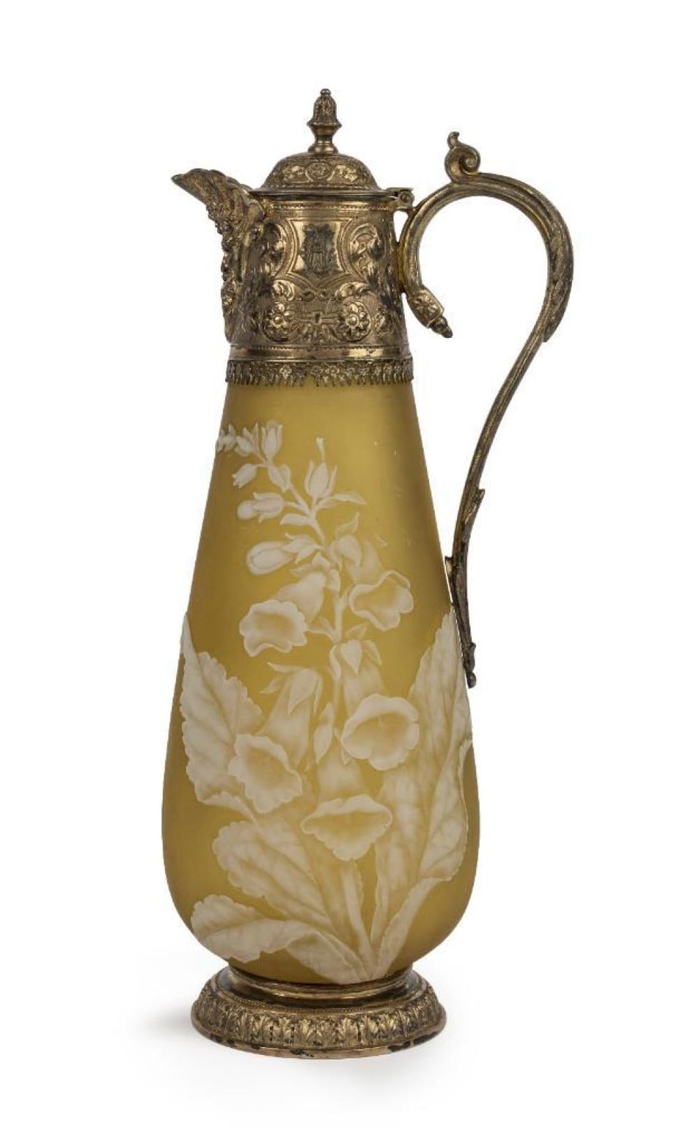 A glass claret jug with an amber body and white floral cameo-style decoration, topped with an ornate metal handle and lid.