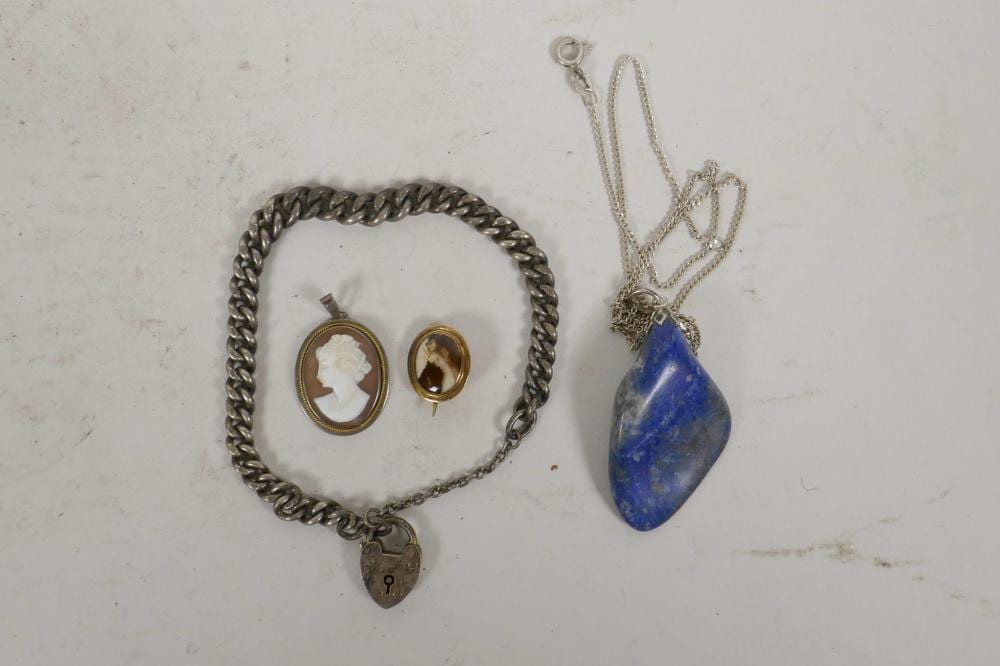 A heavy gauge sterling silver heart lock bracelet, 7¾", 19g, together with a lapiz lazuli pendant necklace on a sterling silver chain, a cameo silver pendant and a small Victorian gold plated enamel brooch, A/F sold by Crow's Auction Gallery Ltd, lot 684 — auction record photograph