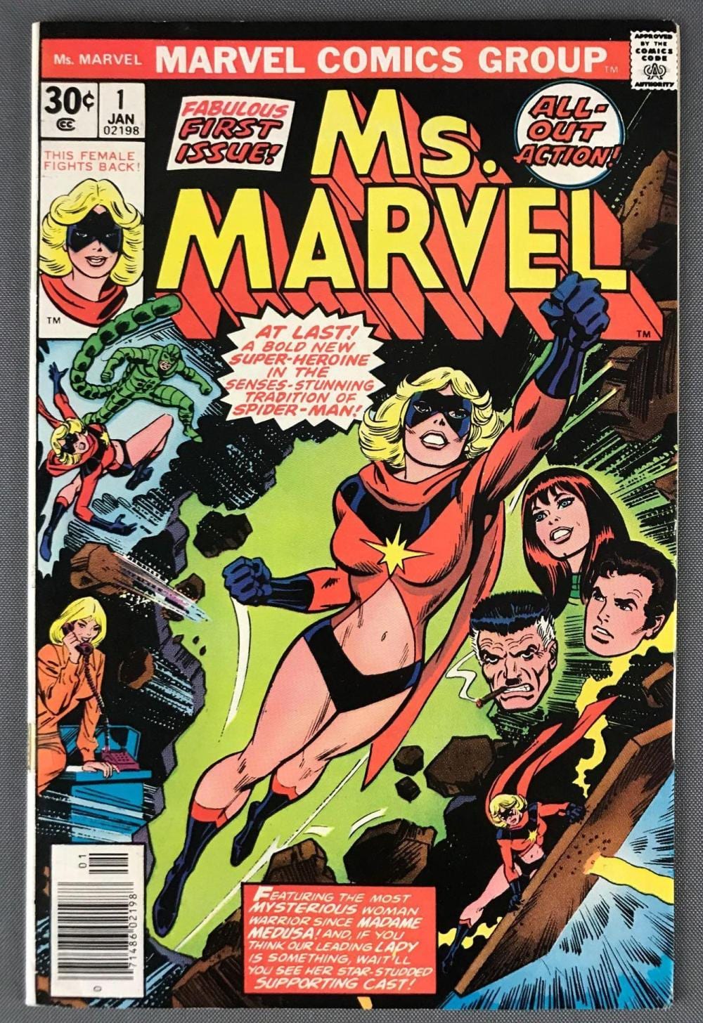 Cover of a Marvel Comics “Ms. Marvel” comic book featuring a blonde woman hero in red and blue battling villains.