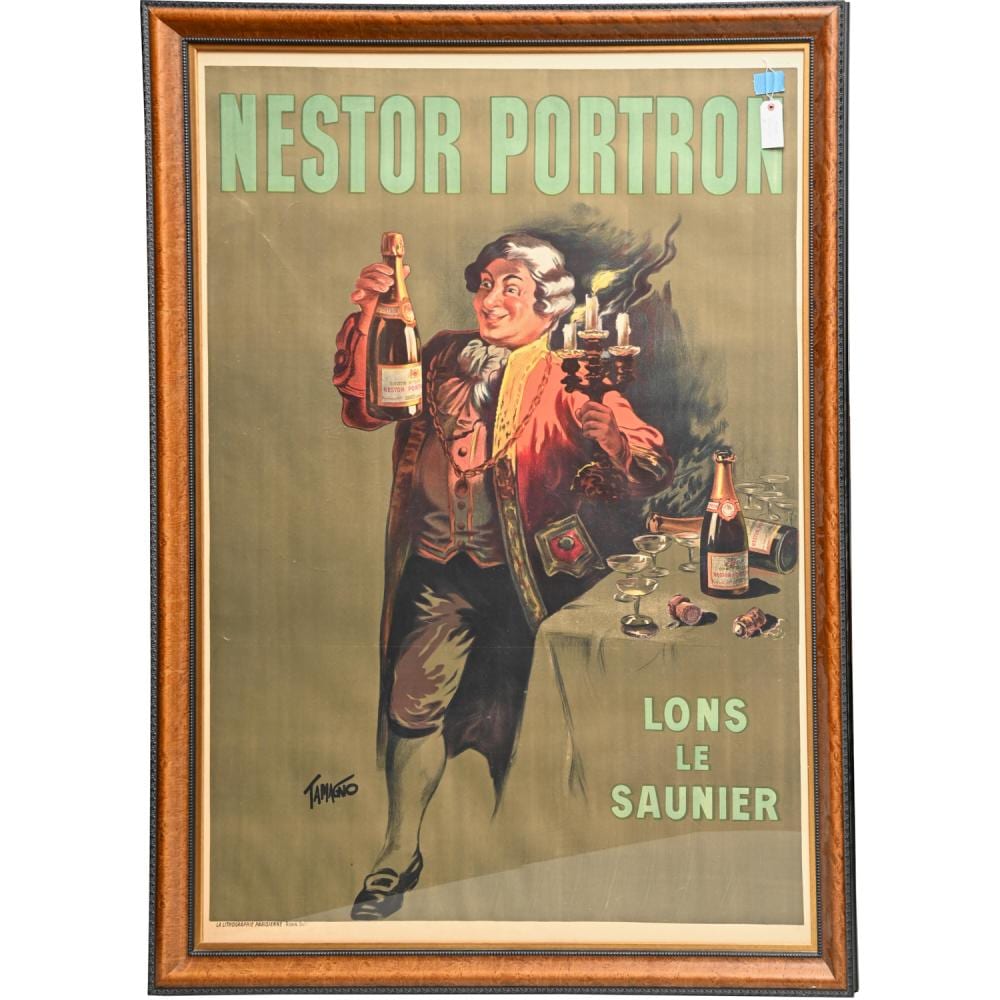 Framed vintage poster featuring a smiling woman holding champagne, with bottles and glasses on a table and French text “NESTOR PORTRON” and “LONS LE SAUNIER.”