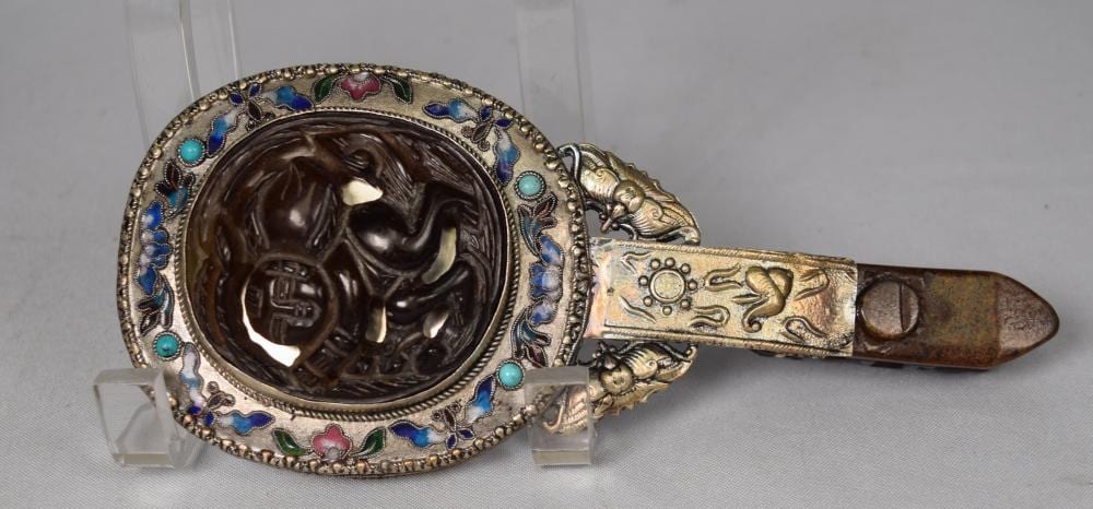 Ornate handheld mirror with a silver-toned round frame in blue, turquoise, and pink enamel and a carved wooden handle.