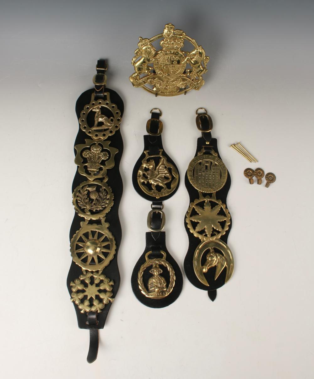 Set of black leather horse bridle parts with gold-toned metal plaques and buckles, shown on a light background.