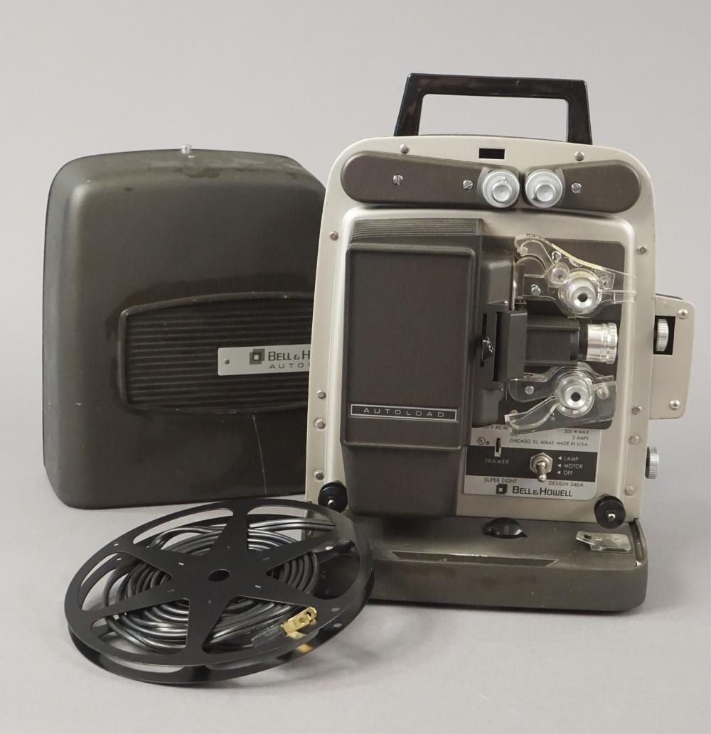 Vintage Bell & Howell Super 8 film movie projector with open housing and film lamp assembly, shown next to its power cord