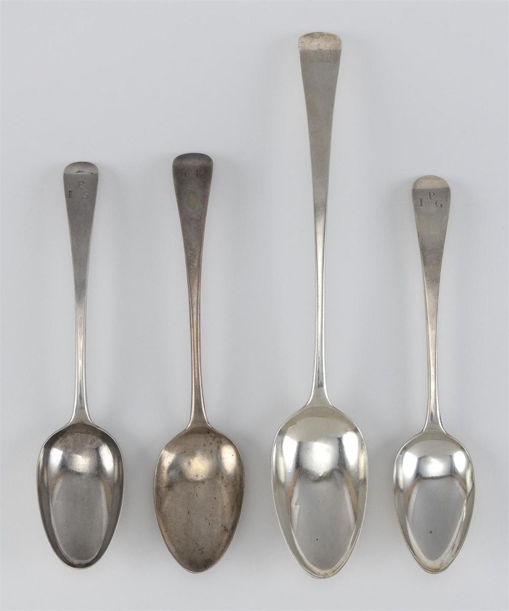 Four silver-tone spoons with oval bowls and engraved marks near the handles, shown against a light background.