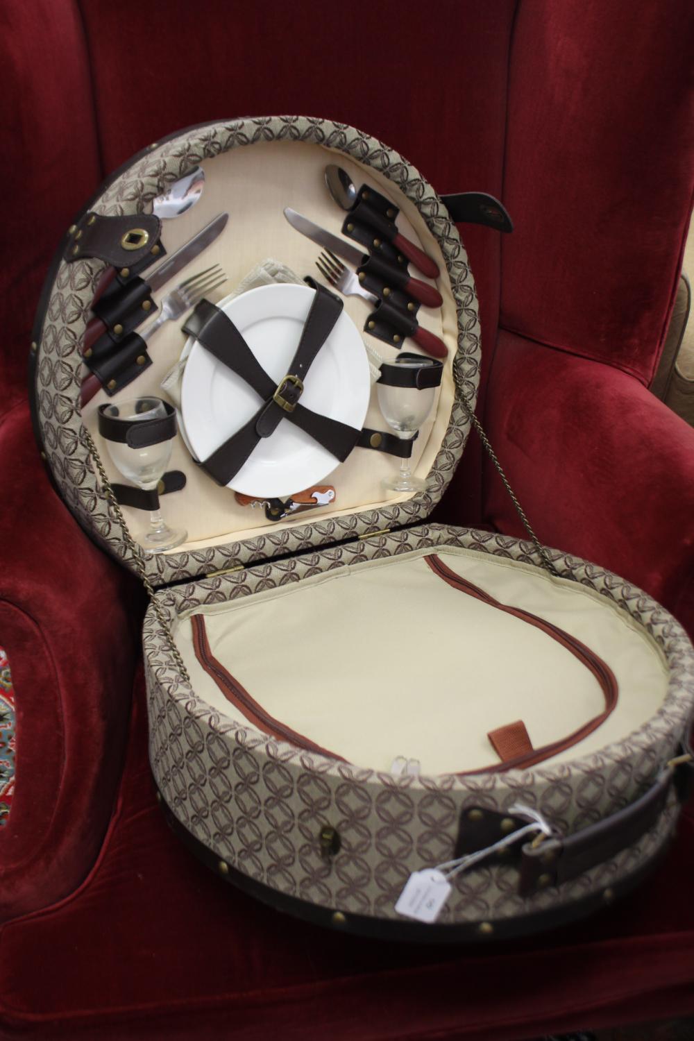 Open picnic basket with fitted cutlery and plates, including knives, forks, glasses, and wrapped utensils.
