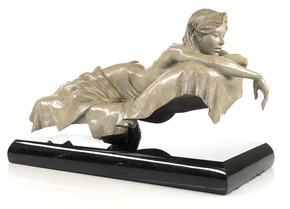 Bronze-style figurative sculpture of a reclining woman resting her arm on a long base, shown in left-facing profile.