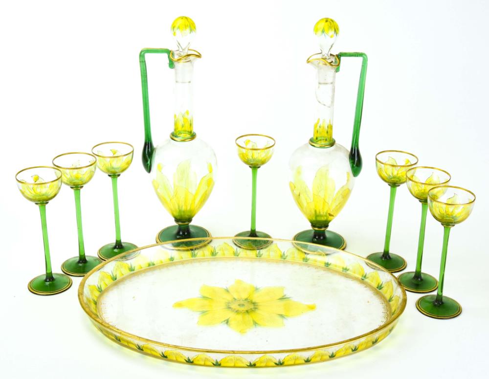Set of green glass decanters and cups with yellow floral decoration, including two bottles, a round tray, and six small goblets.