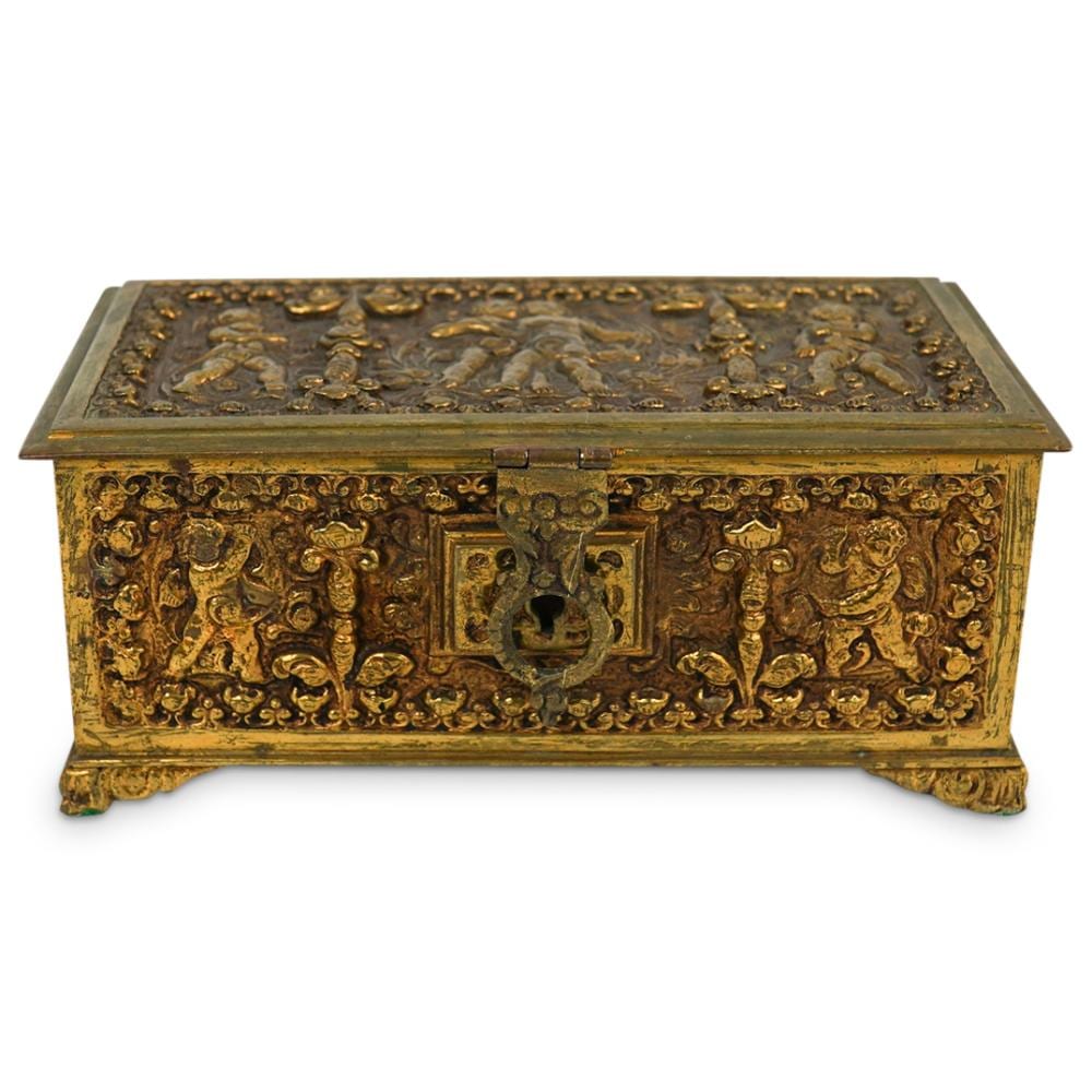 Antique-looking gilt bronze jewelry box with ornate embossed scenes and a rectangular keyhole on the front.