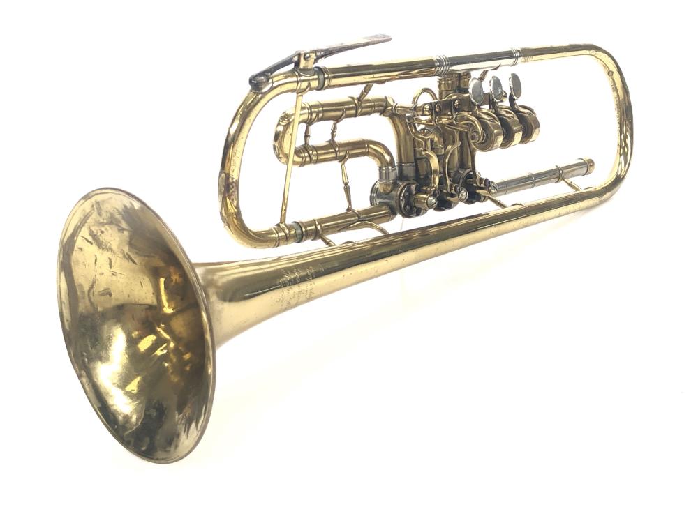 Vintage brass trumpet with three piston valves and bell facing left, shown against a white background.