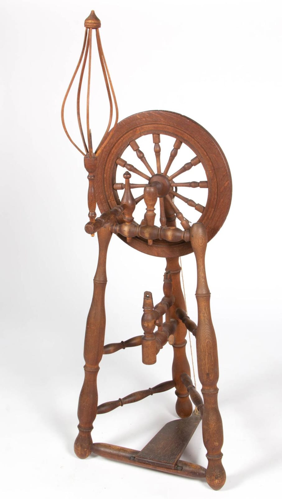Wooden upright flax spinning wheel with a large circular wheel and multiple spokes, shown standing on a base.