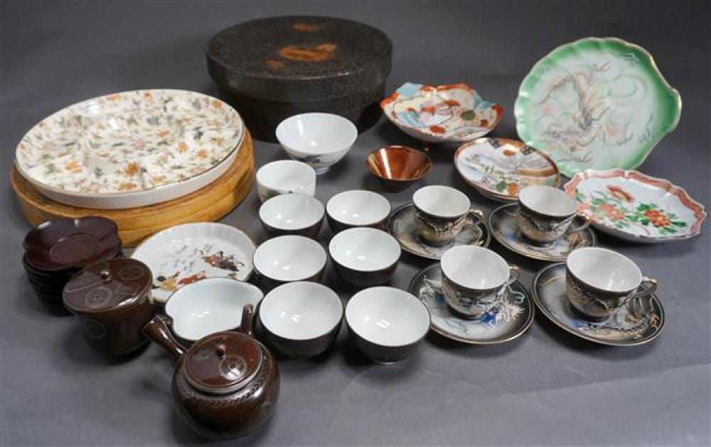 Photograph of a group of small tea and table items, including demitasse cups and saucers, teapot and bowls, with colorful painted porcelain decoration.