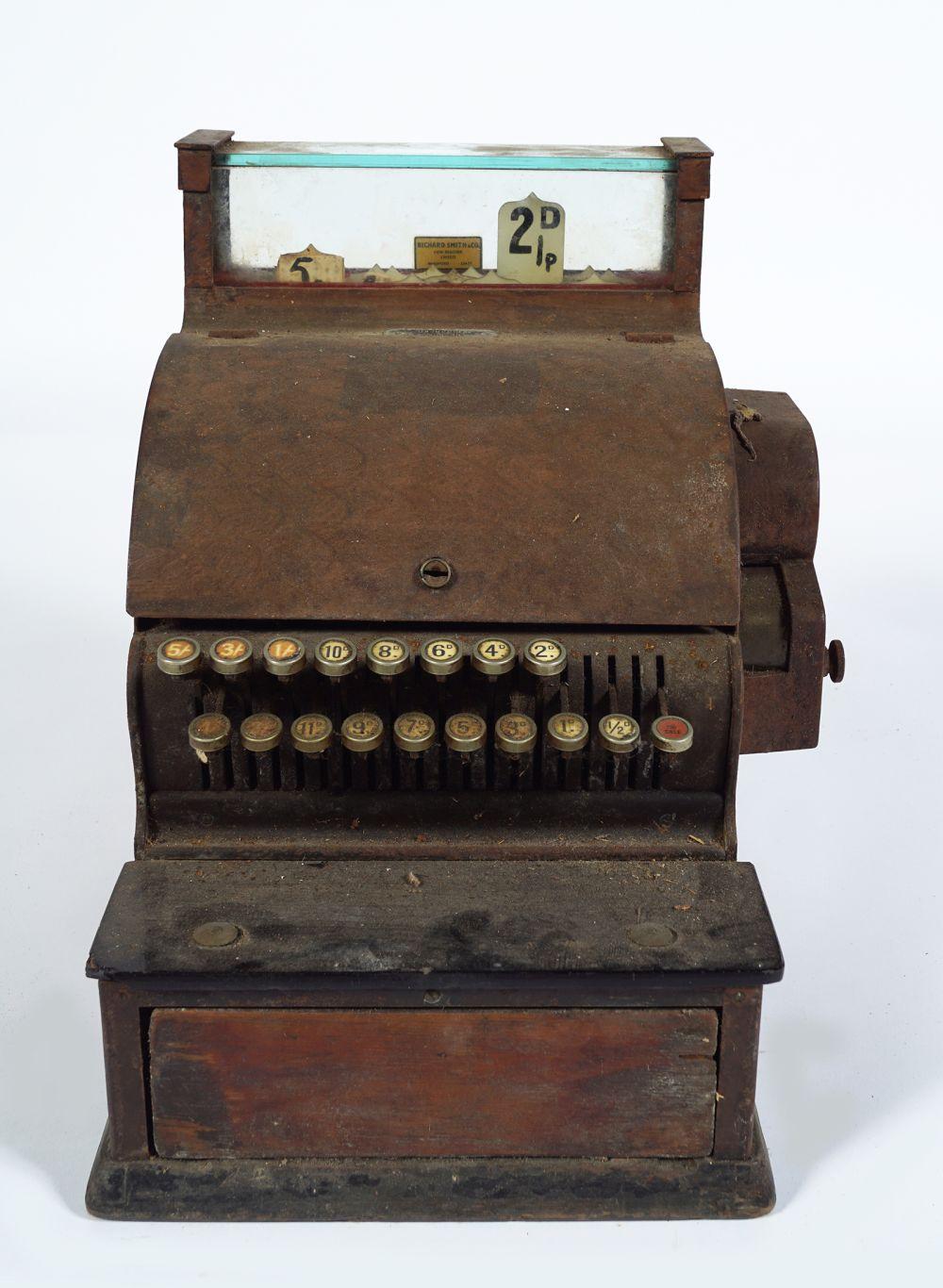 Antique wooden cash register with a row of numbered keys and drawers, shown from the front.