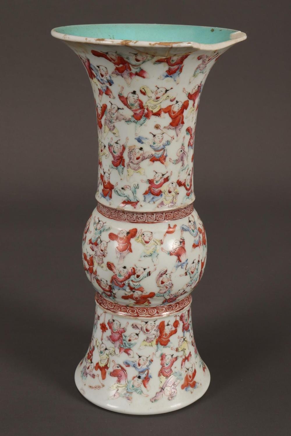 White Chinese porcelain vase with a turquoise rim and red-blue painted figures dancing, shown on a dark background.