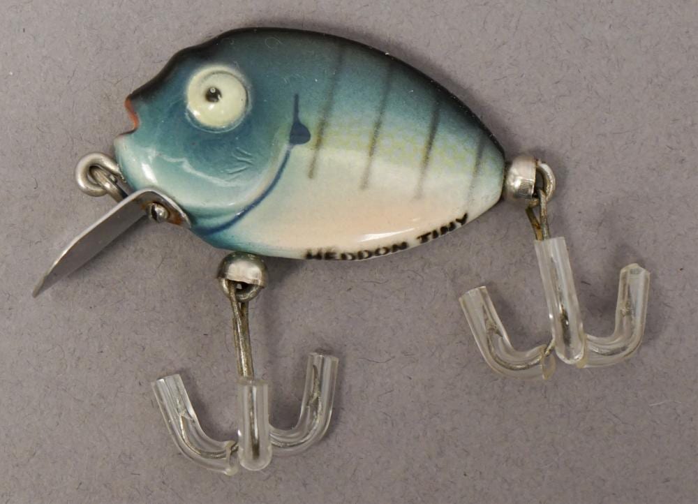 Blue and white fishing lure with a painted eye, metal hooks, and clear treble hook guards on a gray background.