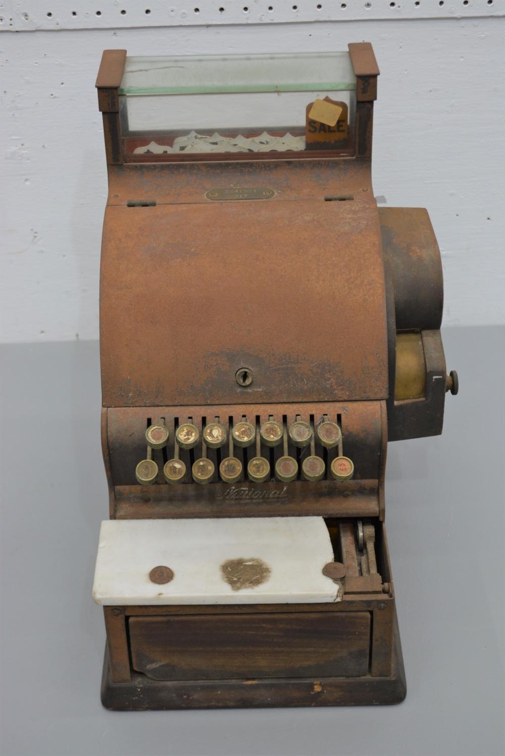 Vintage brown National cash register with display window, dial, and rows of round coin or cash buttons.