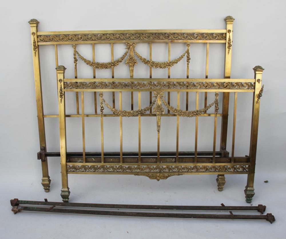 Antique-style brass bed frame with ornate scrollwork and vertical slats, shown front view against a light background.