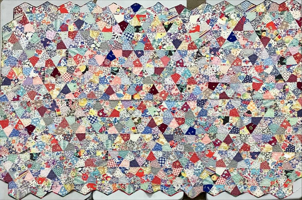 Close-up of a patchwork quilt made of small pieced squares and triangles in many colors, with a multicolor patterned surface.