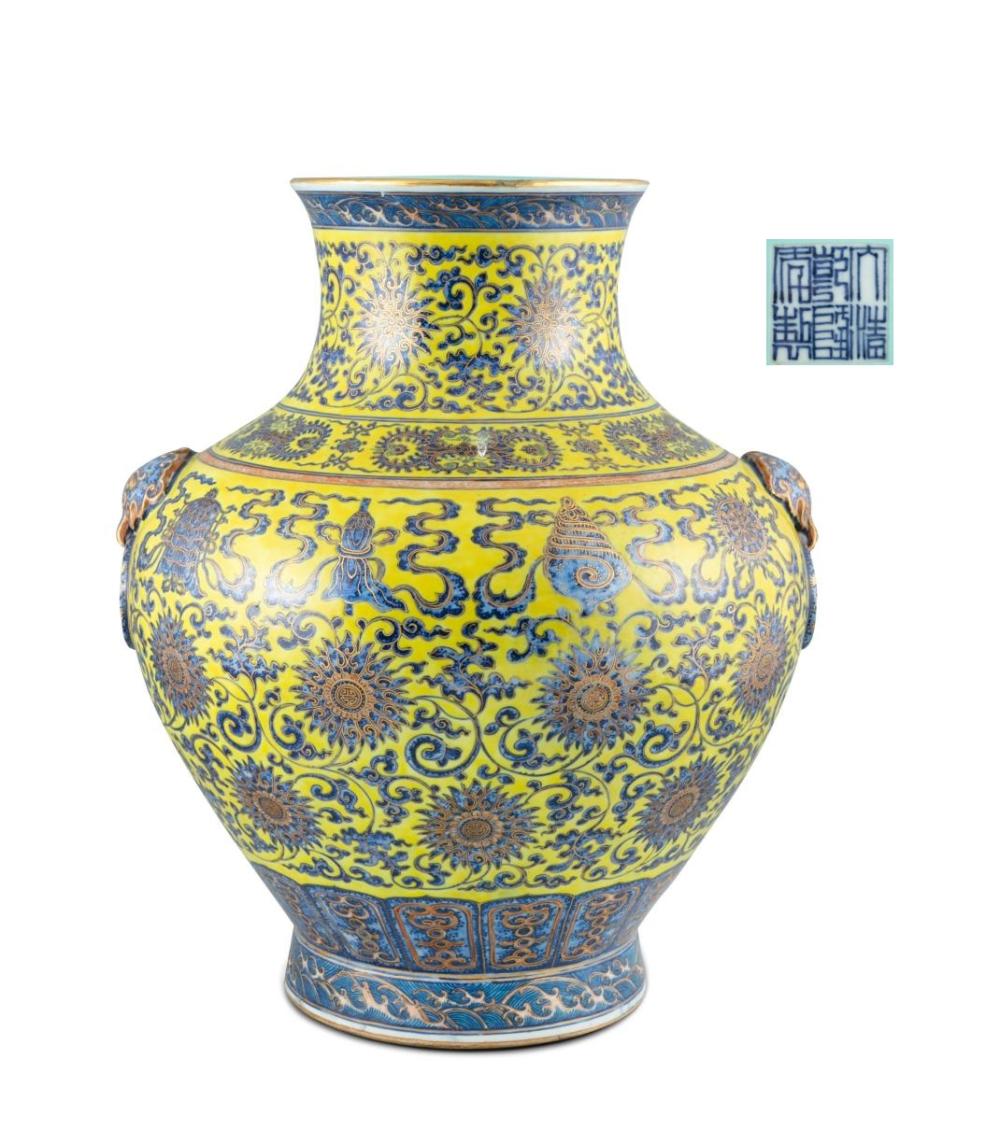 A MASSIVE COBALT BLUE DECORATED YELLOW GROUND ‘LOTUS AND EIGHT TREASURES OF BUDDHISM’ PORCELAIN VASE China, 20th century Of archaistic hu vessel shape, resting on a tall spread foot, with a globular body flanked by two beast face shaped handles and sold by Adam's, lot 114 — auction record photograph