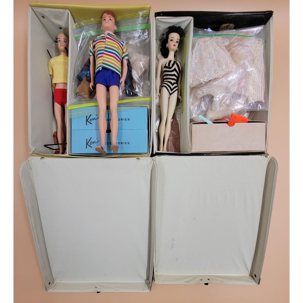 Four fashion dolls in open boxes, including a striped black-and-white dress doll and a colorful striped sweater doll, with extra clothing inside.